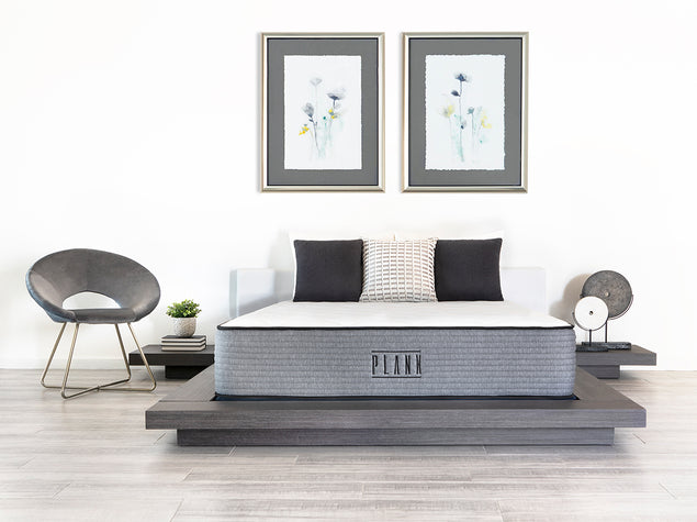The Firm & Extra Firm flippable Plank Luxe Hybrid mattress by Brooklyn Bedding laying on a platform bed with pillows in a master bedroom with artwork on the walls.