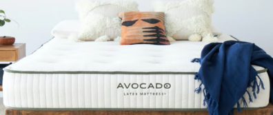 The Avocado 100% Organic Latex mattress on a platform bedframe with a blue blanket and pillows in a master bedroom