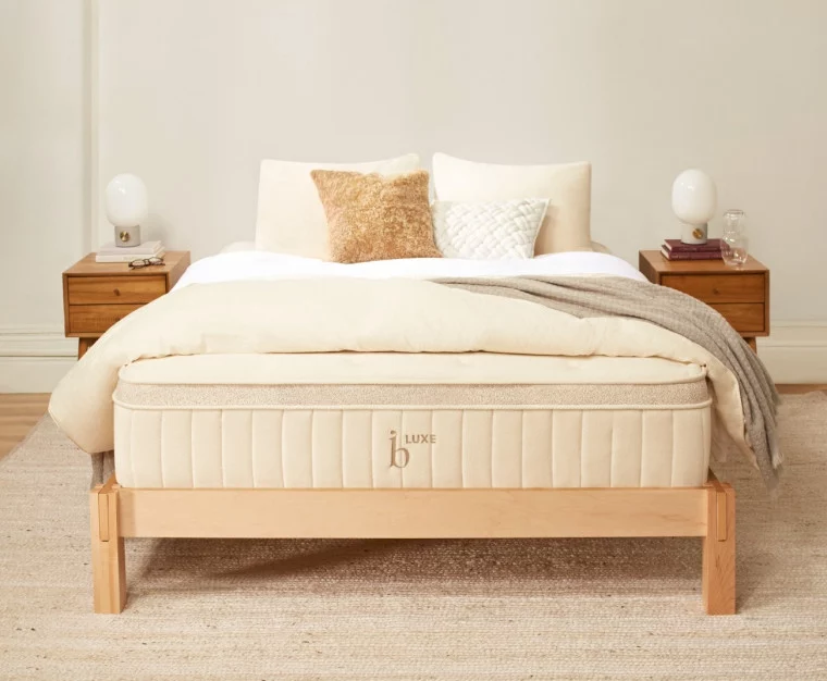 Birch Luxe Natural Latex Mattress by Helix is resting on a natural wood bedframe in a master bedroom with end tables, pillows and sheets. The Birch Luxe is a number one seller for Helix and their first venture into the natural and organic market. The Birch Luxe holds several organic and natural latex certificates and awards.