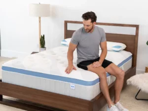 Man sitting on Star Hybrid edge of the mattress to demonstrate the robust edge support.